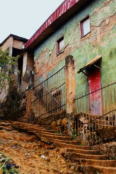 Old and decrepited houses on a steep hill in a poor neighborhood of a tropical third world country, with dirt or earth staircase, scary place.