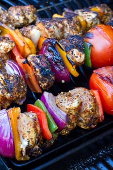 chicken and pepper kebabs slowly cooking on the barbecue