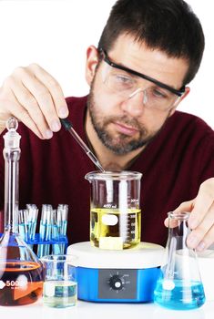 Middle aged man, scientist, researcher or chemist, adding a drop of a chemical to the liquid in the beaker, laboratory setting with glassware, focus on dropper.