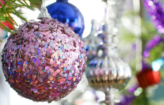 Candid shot of traditional natural fir Christmas tree ornaments with focus on pink bauble, perfect holiday background or for card.