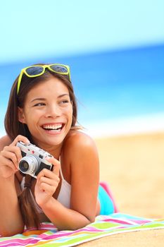 Summer beach woman fun holding vintage retro camera laughing and smiling happy during summer holiday vacation travel.