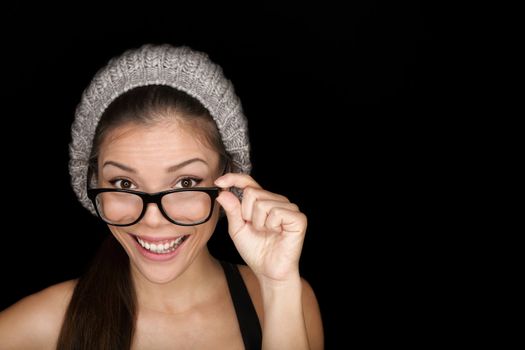 Cool hipster student woman wearing eyewear glasses and knit hat isolated on black background in studio. Beautiful multiracial mixed race Asian Chinese / Caucasian female university student looking at camera smiling happy.