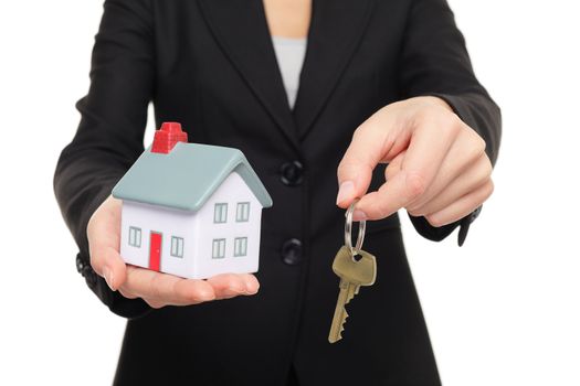 Real estate agent new house keys concept. Realtor showing holding house keys and mini house model. Buying new home conceptual image with business woman in suit isolated on white background