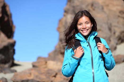 People hiking. Hiker woman looking at camera smiling happy portrait. Multicultural young woman walking in mountains with backpack