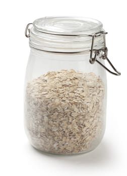 Oat flakes in the transparent glass jar on the white