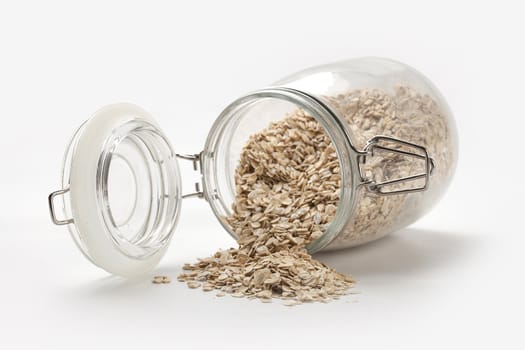 Oat flakes in the transparent glass jar on the white