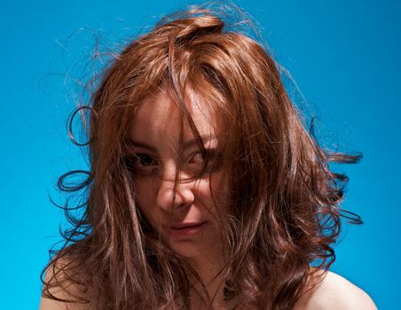 Attractive Young Girl with Tousled Hair closeup on blue background