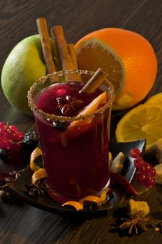 Arrangement of Fruits with Red Currant, Apple and Orange with Glass of Mulled Wine and Cinnamon Stick, Slice of Orange and Anise Star closeup on Dark Wood background