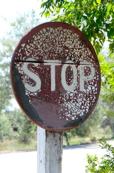Close-up of old, peeling stop-sign in very rough condition
