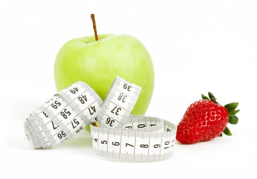 Measuring tape wrapped around a green apple and strawberry as a symbol of diet concept