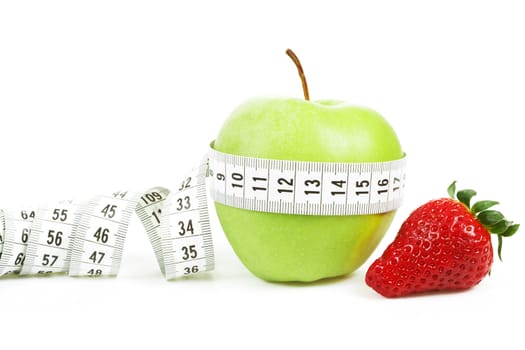 Measuring tape wrapped around a green apple and strawberry as a symbol of diet concept