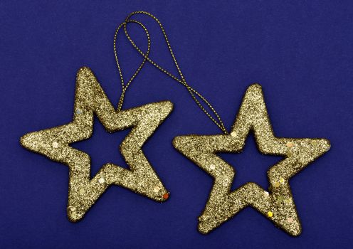 Golden glittering star Christmas ornament isolated on a blue background