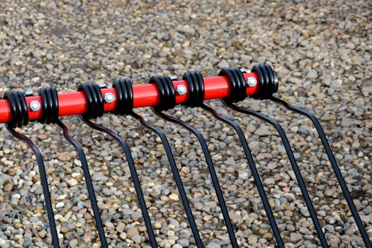 Red rake attachment over stone