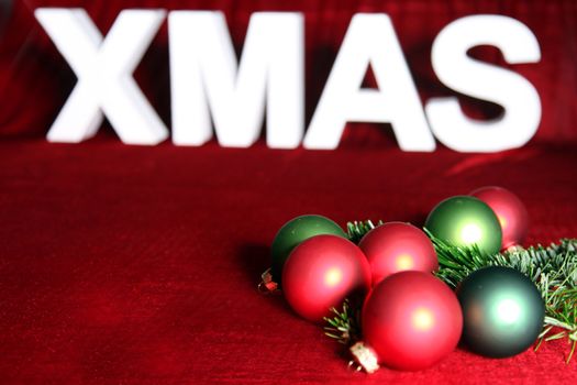 Colorful Christmas baubles and pine needles for decoration, on red