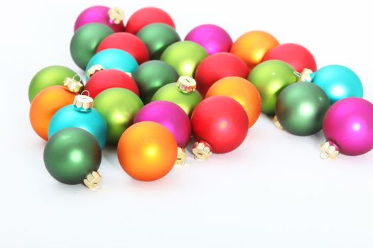 Scattered multicolored Christmas baubles on a white surface