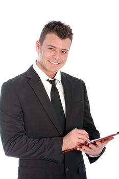 Confident handsome young businessman standing writing notes on a clipboard smiling at the camera, upper body studio portrait isolated on white