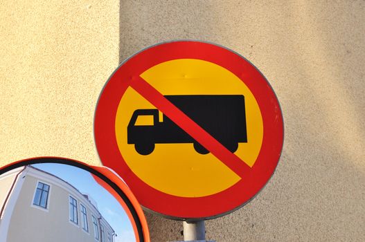 Blind driveway mirror and a no truck sign in a street corner.