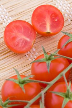 Closeup on fresh small cocktail tomatoes on a straw braided mat