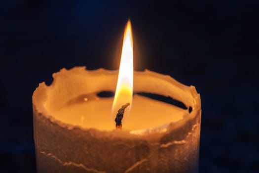 Macro of a beautiful glowing burning candle in the darkness