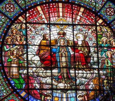 Stained glass Jesus crowning Mary angels God the father in rose window basilica inside Monestir Monastery of Montserrat, Barcelona, Catolonia, Spain.  Founded in the 9th Century, destroyed in 1811 when French invaded Spain. Rebuilt in 1844 and now a Benedictine Monastery.  Placa de Santa Maria