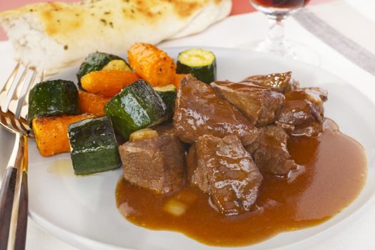 Classic of Belgian cuisine, carbonnade de boeuf a la Flamande is beef simply cooked in beer. Here served with roasted carrots and courgettes, crusty bread and a glass of beer, it's absolutely delicious!