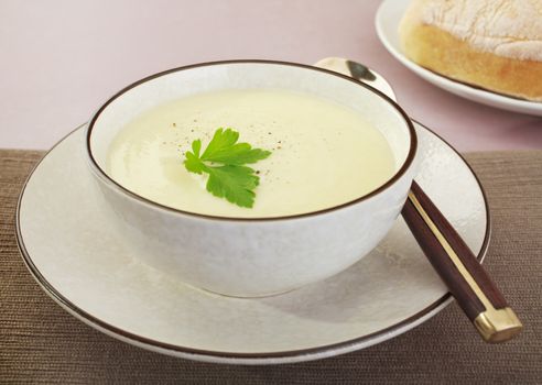 A bowl of creamy cauliflower soup with bread.