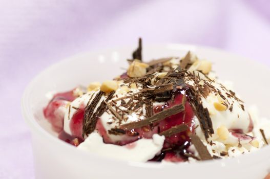Dessert with cream, chocolate shaving, red jam and grated nuts