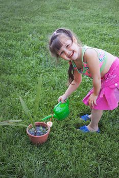 Little girl watering the plants in the garden