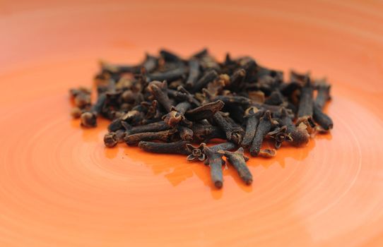 Scented clove spices on orange plate