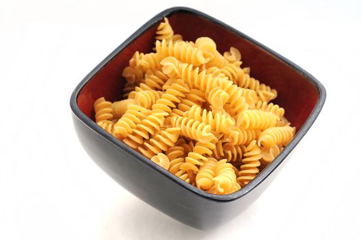 Rotelli pasta in red bowl on white background