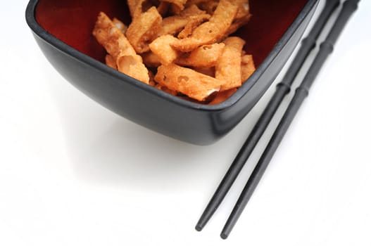 Fried wonton strips or Chinese food in bowl with chopsticks