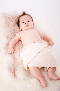 cute little baby infant toddler lying on white blanket smiling portrait