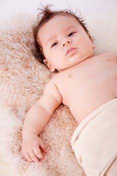 cute little baby infant toddler lying on white blanket smiling portrait