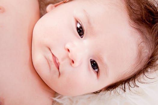 cute little baby infant toddler lying on white blanket smiling portrait