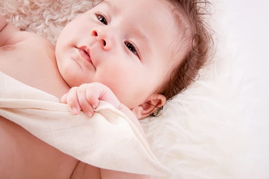 cute little baby infant toddler lying on white blanket smiling portrait