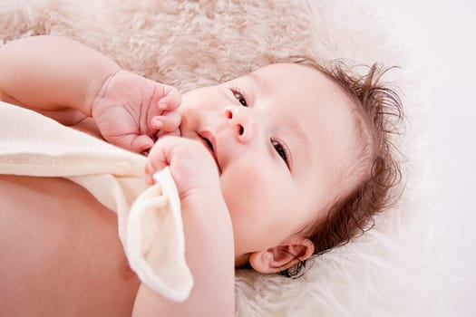 cute little baby infant toddler lying on white blanket smiling portrait