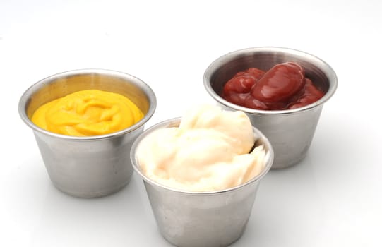 Ketchup, mustard and mayonnaise in small metal bowls