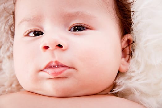 cute little baby infant toddler lying on white blanket smiling portrait