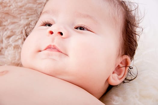 cute little baby infant toddler lying on white blanket smiling portrait