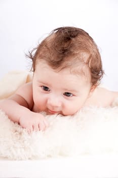 cute little baby infant toddler lying on white blanket smiling portrait