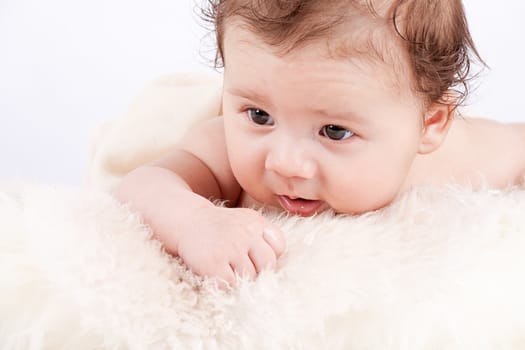 cute little baby infant toddler lying on white blanket smiling portrait