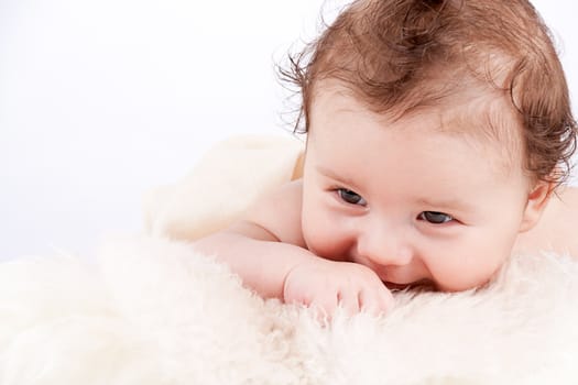 cute little baby infant toddler lying on white blanket smiling portrait