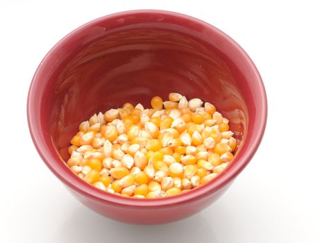 Raw popcorn in a red bowl isolated with nobody