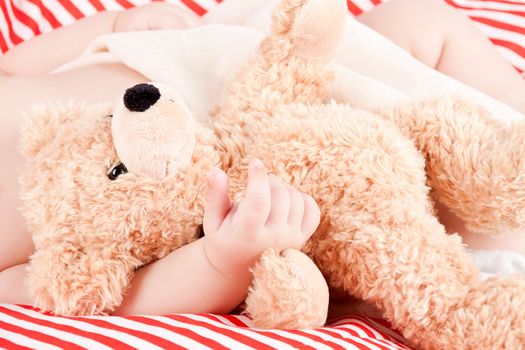 sleeping cute little baby on red and white stripes pillow with teddy bear