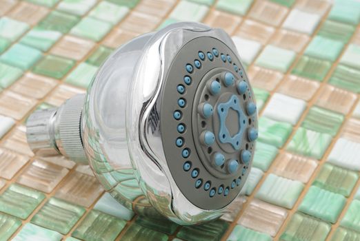Showerhead on green and white tile background
