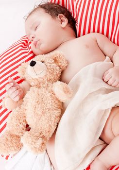 sleeping cute little baby on red and white stripes pillow with teddy bear
