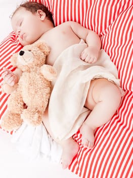 sleeping cute little baby on red and white stripes pillow with teddy bear