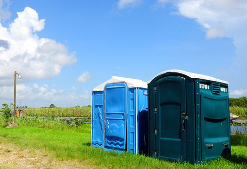 Green and blue outhouses near a river