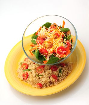 Healthy vegetarian meal that consists of a bowl of salad and a plate of quinoa with tomatoes and basil