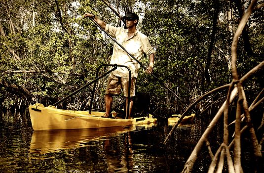 Man paddling down river in yellow kayak for a fishing excursion